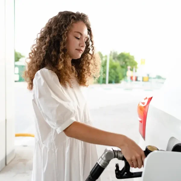 young-curly-woman-refueling-car-at-gas-station-2023-11-27-05-19-30-utc